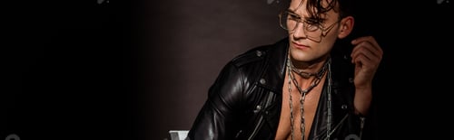 Preview: panoramic shot of pensive young man in leather jacket sitting on black