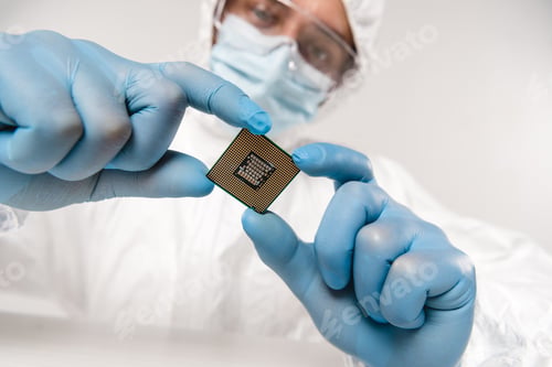 Preview: selective focus of microchip in hands of scientist wearing latex gloves, googles and mask on grey