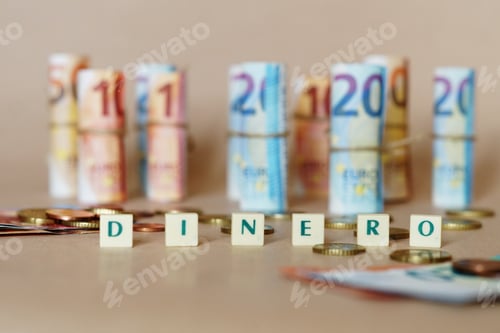 Preview: Cubes spelling Dinero in front of Spanish dinero bills and coins on the table