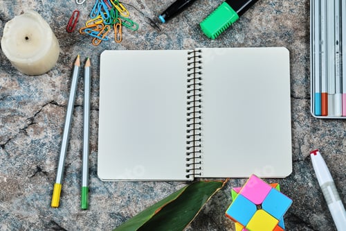 Preview: Empty notebook with pencils, candle, paper clips on the marble background