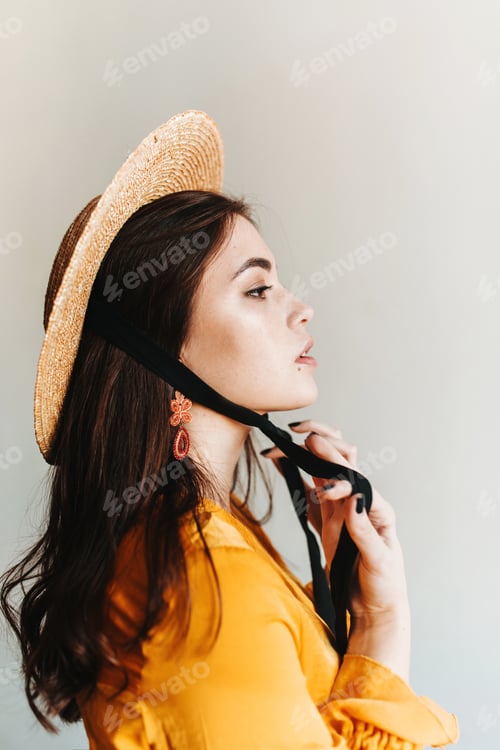 Vista previa: Foto de perfil de una orgullosa chica europea de pelo largo con sombrero naranja. Mujer aristócrata en barquero posando