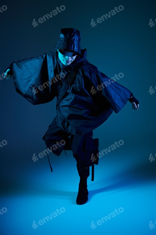 Preview: Stylish young asian man in modern outfit striking a dynamic pose against a blue background