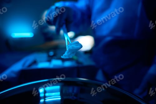 Preview: Unrecognizable surgeon holding clamp with swab during surgery operation