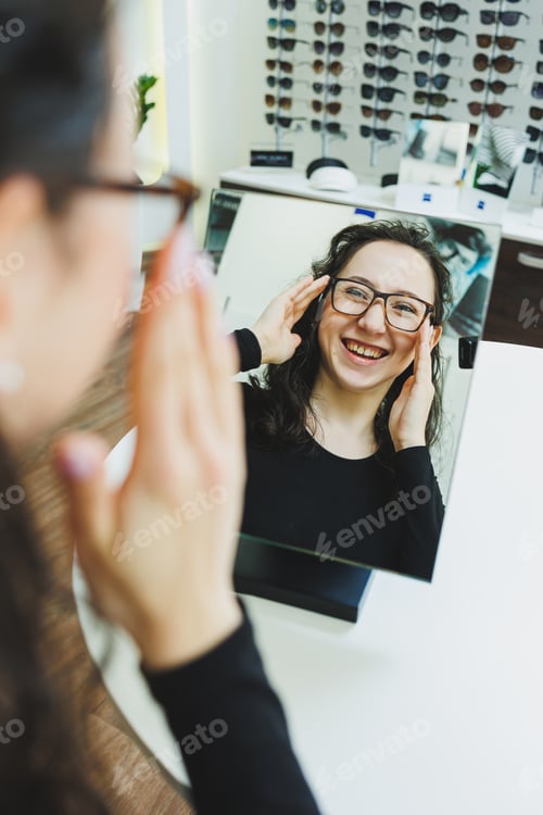 Preview: Optics shop. A young woman chooses glasses in an optical store. Stand with glasses. Vision