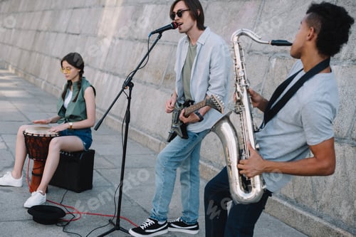 Preview: Team of young friends musicians playing and singing in urban environment