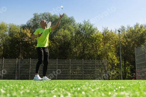 Preview: White badminton shuttlecock and badminton racket in man hands. Outdoors. Close up.