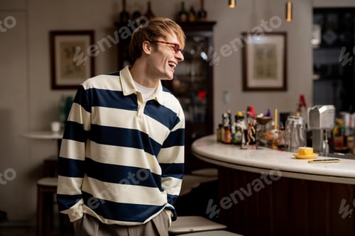 Preview: Young man enjoys a moment of laughter in a modern cafe setting