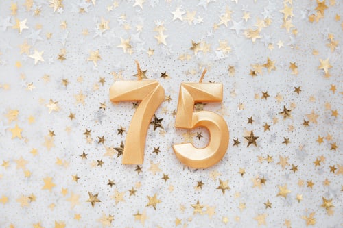Preview: Number 75 seventy five golden celebration birthday candle on Festive Background.