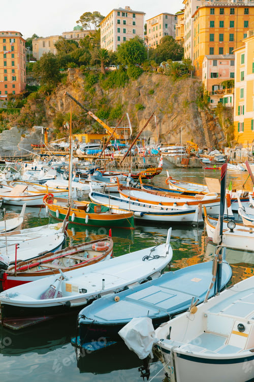 Preview: Colorful boats floating in camogli harbor at sunset with buildings overlooking the scene