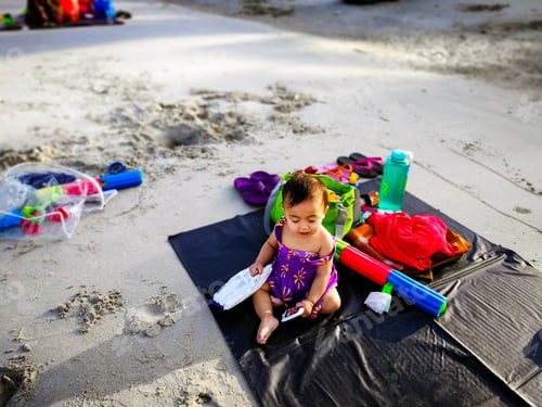 Preview: baby on the black mat at the beach