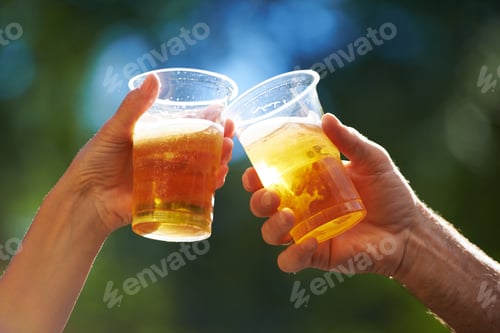 Preview: Enjoying a cold one. Cropped view of two people saying cheers with their beer cups.