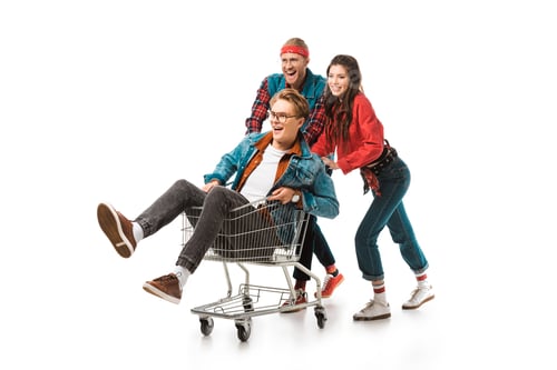 Preview: happy young hipsters having fun with shopping cart isolated on white
