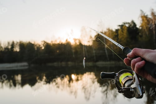 Preview: Fisherman with rod throws bait into the water on river bank. Fishing for pike, perch. Background wil