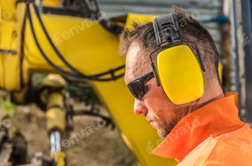 Construction Worker Wearing Ear Protection Working on Machinery