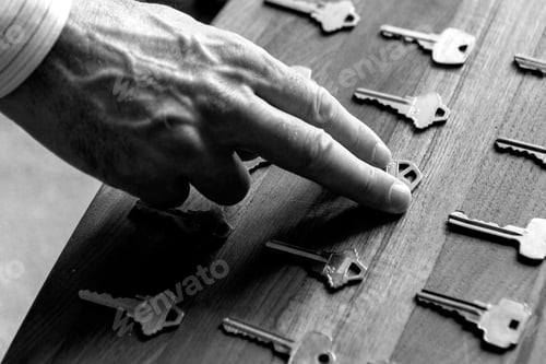 Preview: Real estate hand picking up a house key in black and white.