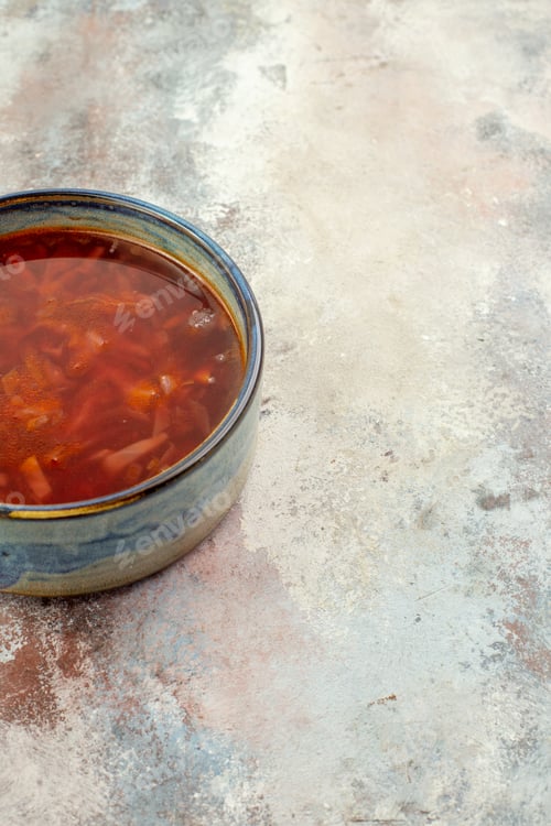 Preview: Half shot of delicious borscht soup on a blue pot on a colorful background in vertical view