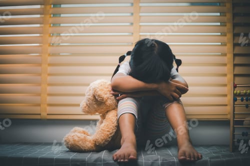Preview: Close up lonely little girl hugging toy, sitting at home alone, upset unhappy child
