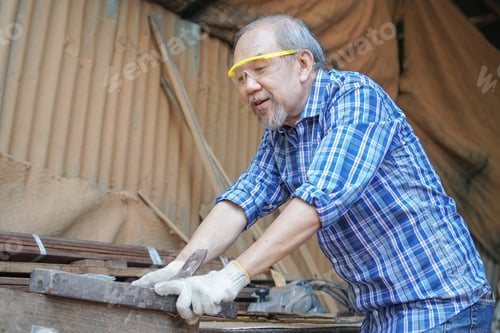Preview: Asian senior male carpenter feeling tired from work at the carpentry workshop