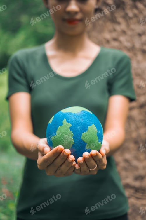 Preview: An Asian woman holds a globe in green forest,symbolizing importance preserving nature.emphasizes