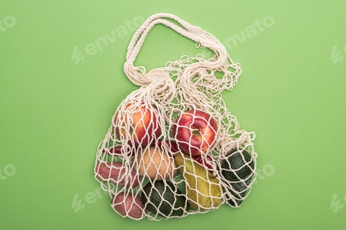 Preview: top view of vegetables and fruits in string bag isolated on green