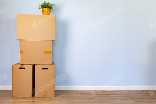 Preview: House moving concept with stacked cardboard boxes in a room