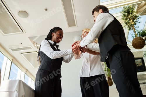 Preview: Multiethnic Young Adult Restaurant Workers Stacking Hands Celebrating Teamwork