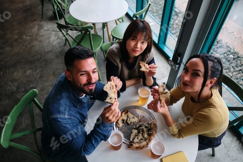 Preview: Friends Enjoying Pizza Together in a Restaurant Gazing at the Lens