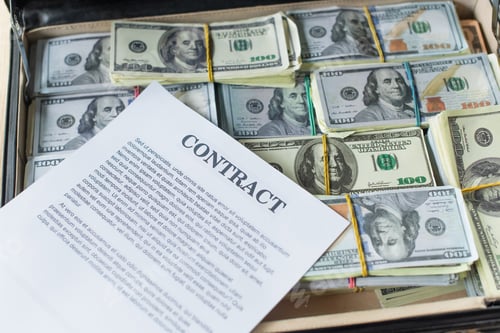 Preview: KYIV, UKRAINE - SEPTEMBER 22, 2021: high angle view of contract on dollar banknotes in briefcase,