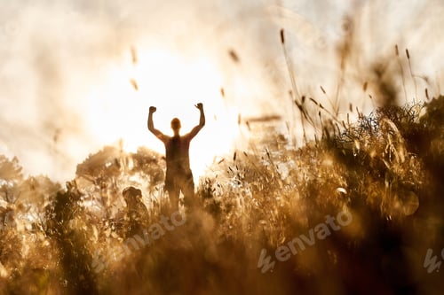 Preview: Rear view shot of a sporty young man celebrating after a workout outside