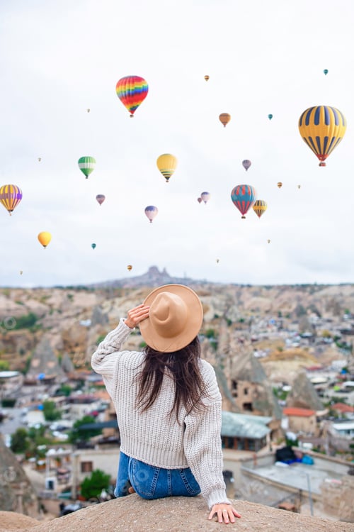 Preview: Happy young woman during sunrise watching hot air balloons in Cappadocia, Turkey