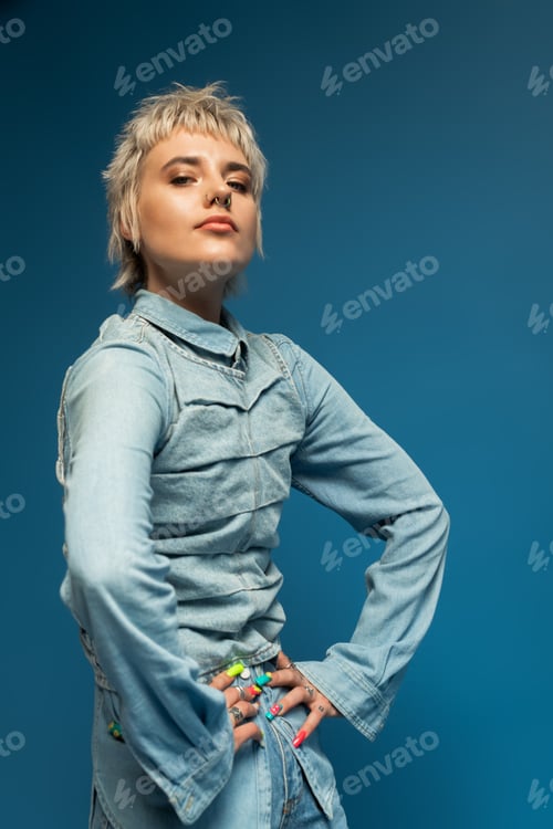 Preview: Stylish young woman posing confidently against a vibrant blue background showcasing modern fashion