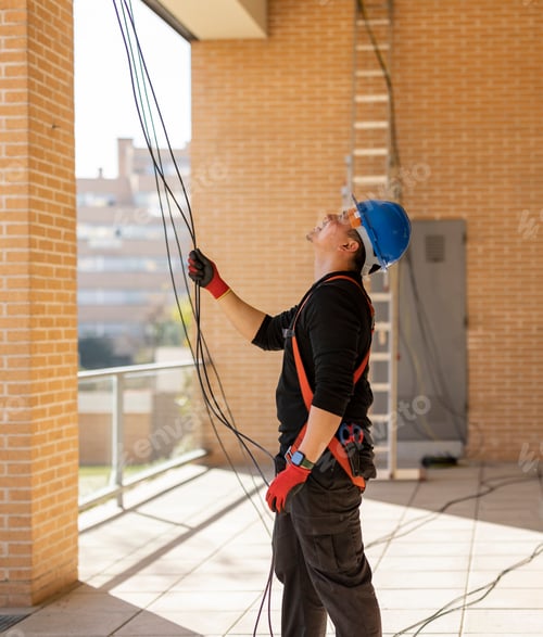 Preview: electrician worker with protective helmet inserting wiring in a building