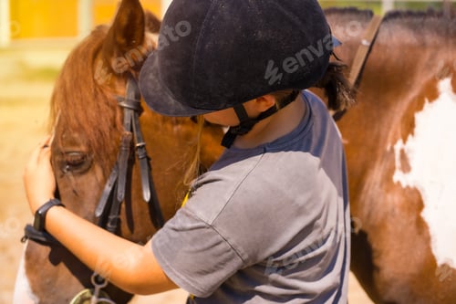 Preview: Caucasian blonde girl on a horse stroking and pampering a brown horse