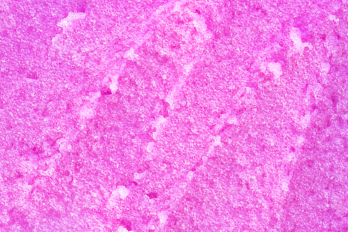 Preview: Texture of raspberry salt scrub, closeup. Texture of body scrub strokes with salt particles.