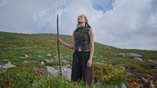 Preview: Dreaming woman standing hill on outdoor journey. Fashion model posing with stick