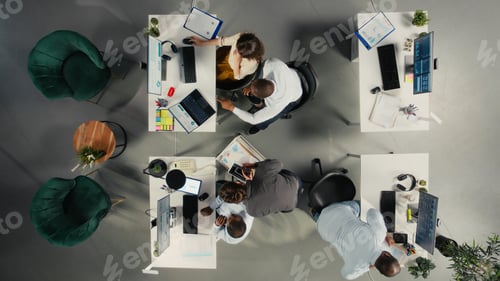 Preview: Top down view of employees reviewing charts and diagrams during briefing