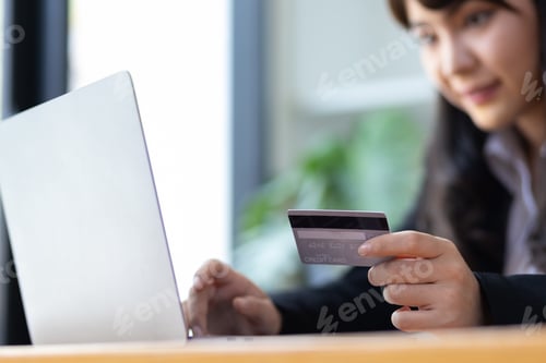 Preview: Woman holding credit card and using laptop. Online payment and online shopping concept.