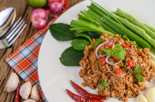 Preview: Spicy Minced Pork Salad on a white plate with lentils, kaffir lime leaves and spring onions.