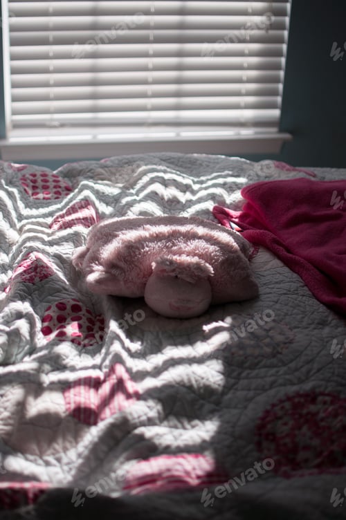 Preview: Pig pillow pet laying on a bed with a cool shadow from the window
