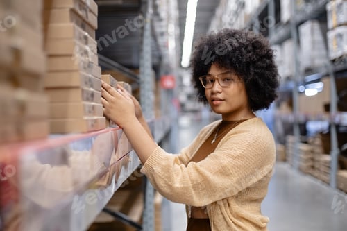 Preview: Young African American female afro hairstyle looking at camera picking up products box paper