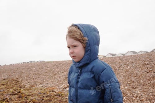 Preview: Boy wearing parka on rocky beach