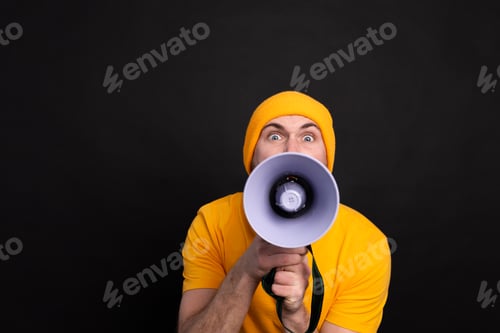 Preview: Attention! European man shouting in megaphone on black background
