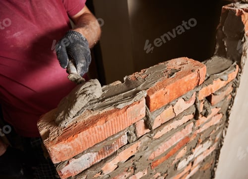 Preview: Male worker building brick wall at constructing site.