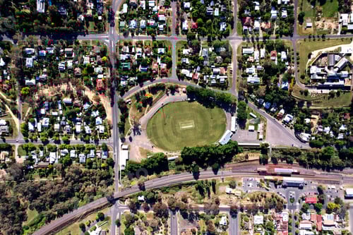 Preview: Drone photo looking down at a small city with a football oval and train station.