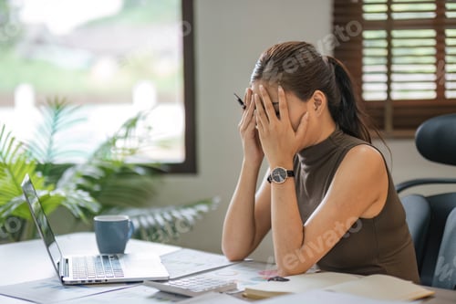 Preview: Young Asian businesswoman working on laptop computer, stressed has a headache and thinks hard from