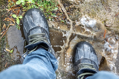 Preview: View from above on pair of trekking shoes in a mud.
