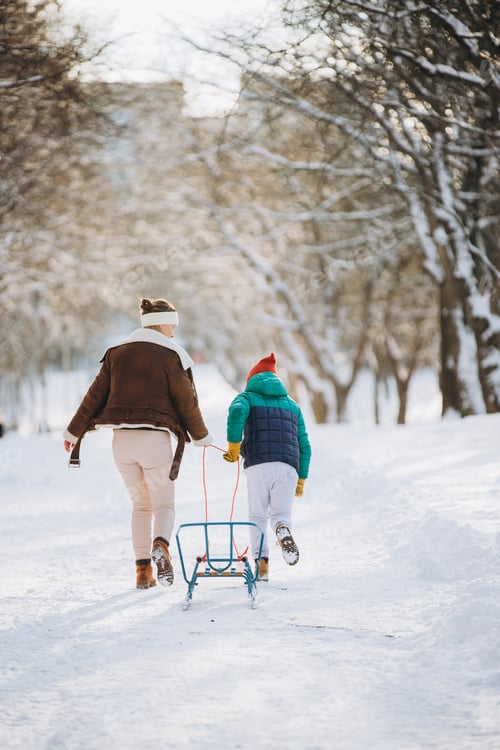 Preview: Mother and son enjoying winter walk pulling sled