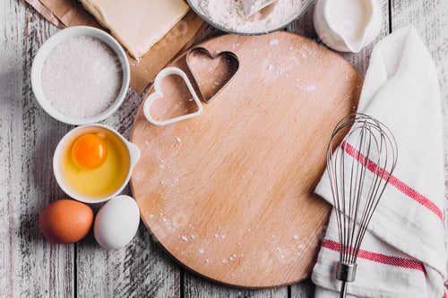 Preview: Ingredients for baking Valentines day cake - eggs, flour, milk, butter, sugar on wooden board.