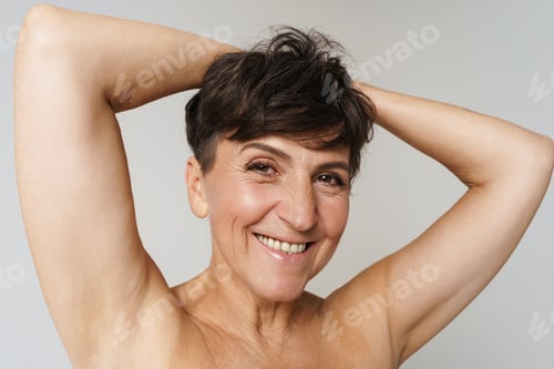 Preview: Mature half-naked woman smiling while showing her armpits
