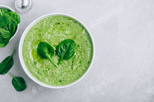 Preview: Green creamy spinach soup on a gray concrete background.